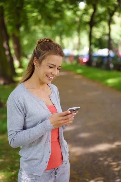 Glad ung kvinna läsa ett meddelande på sin mobil — Stockfoto