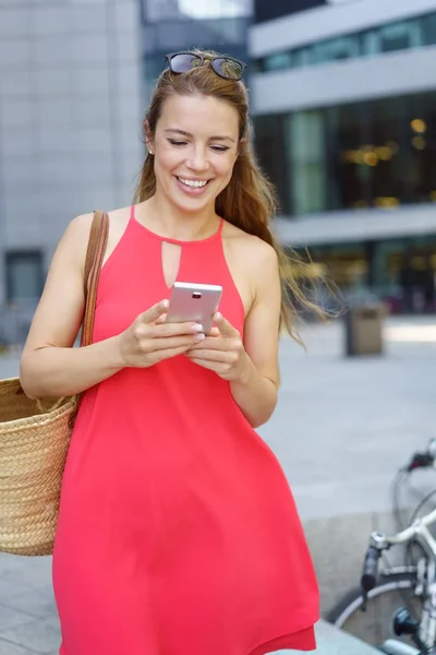 Young woman walking through town with a mobile — Stock Photo, Image