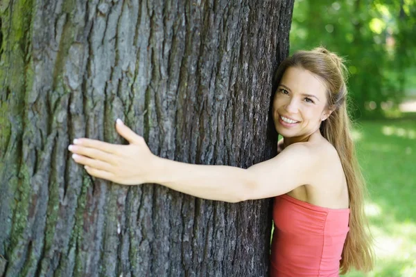 Mujer joven con pelo largo y rubio abrazando el árbol — Foto de Stock