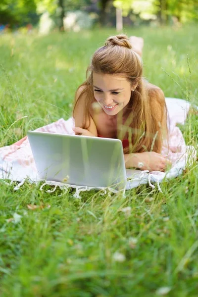 Young woman using laptop while lying on grass — Stock Photo, Image