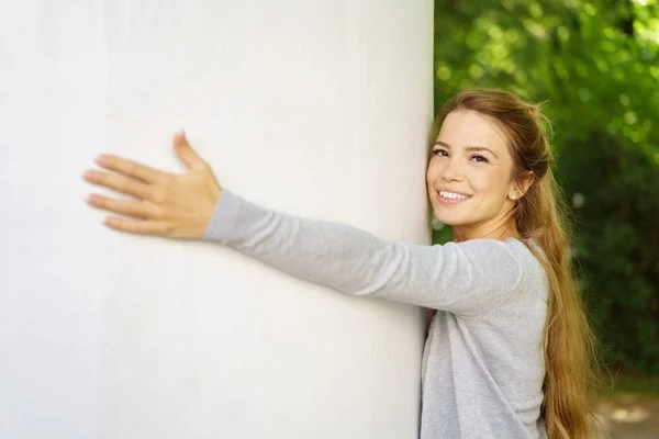 Cheerful woman embracing white column — Stock Photo, Image