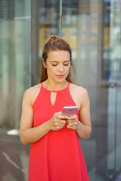 Schicke junge Frau liest SMS auf ihrem Handy — Stockfoto