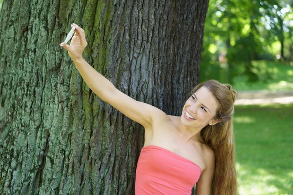 Jovem sorrindo mulher tomando selfie no parque — Fotografia de Stock