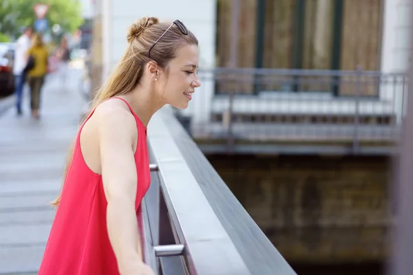 Junge Frau blickt über eine städtische Brücke — Stockfoto