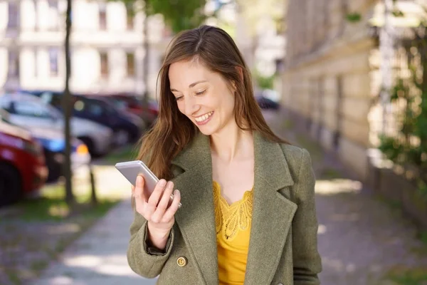 Junge Frau liest eine SMS mit einem Lächeln — Stockfoto