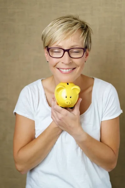 Blondine mit kurzen Haaren hält Sparschwein — Stockfoto