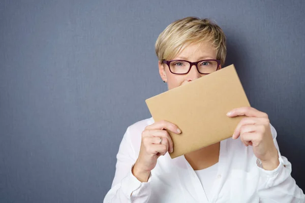 Vrouw met een lege bruin kaart aan haar gezicht — Stockfoto