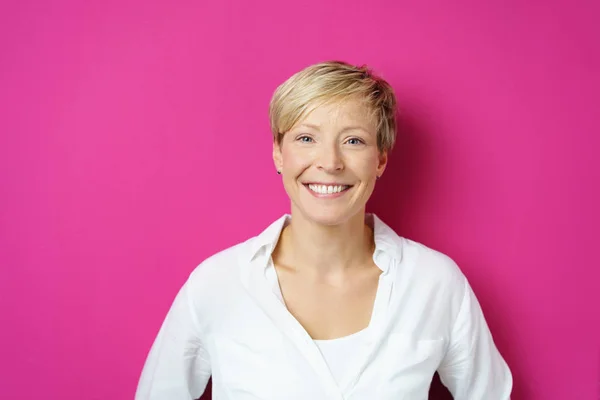Взрослая улыбающаяся женщина на розовом фоне — стоковое фото