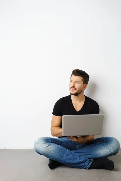 Přemýšlivý muž sedící na podlaze s notebookem — Stock fotografie