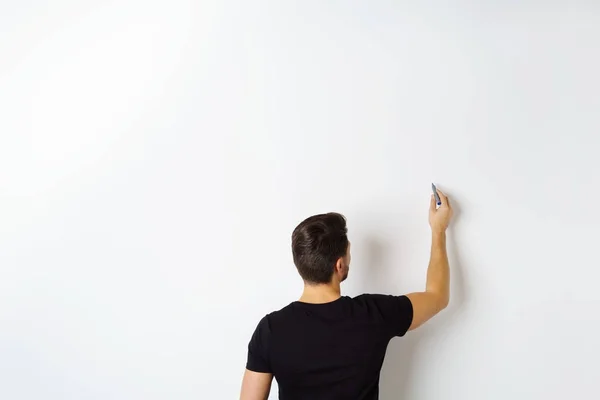 Homme écrivant sur un mur blanc — Photo