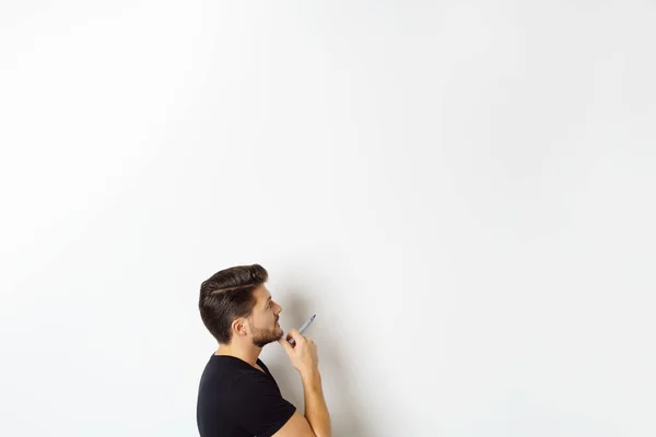 Nadenkende man met marker pen staande door muur — Stockfoto