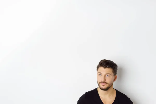 Beyaz duvar dibinde oturan genç düşünceli adam — Stok fotoğraf