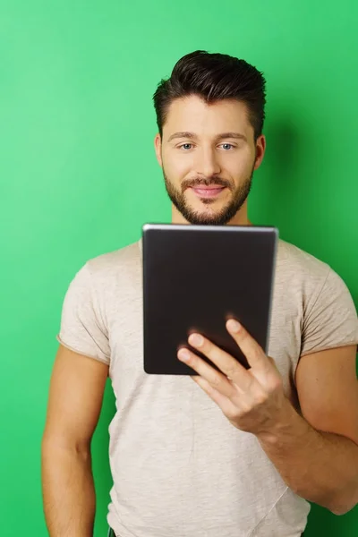 Чоловік тримає планшет на зеленому тлі — стокове фото
