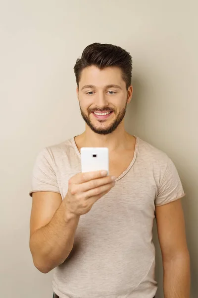 Jeune homme joyeux utilisant un smartphone — Photo