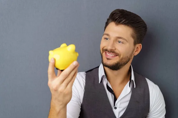 Young cheerful man holding piggy bank — Stock Photo, Image