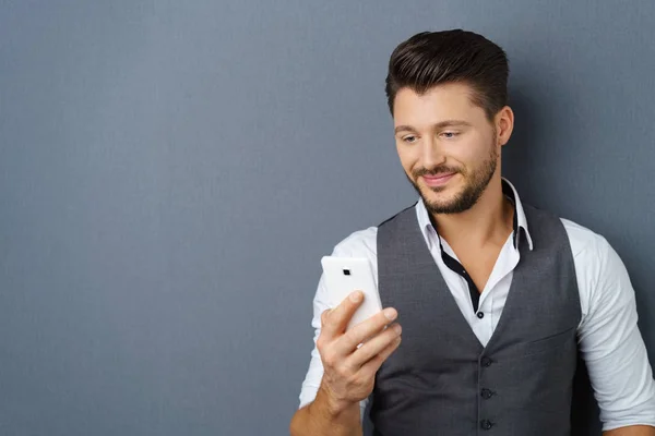 Молодой бородатый мужчина смотрит в телефон — стоковое фото