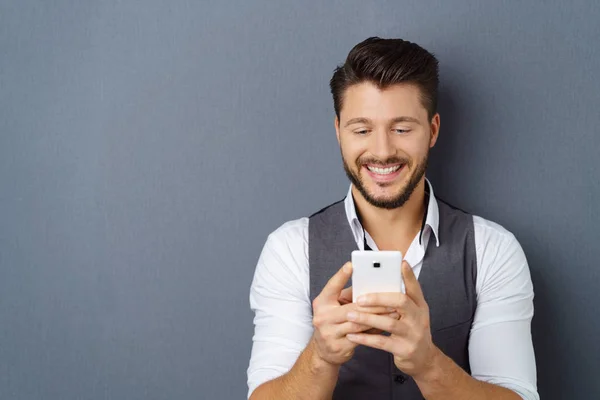 Estúdio tiro de jovem homem feliz usando smartphone — Fotografia de Stock