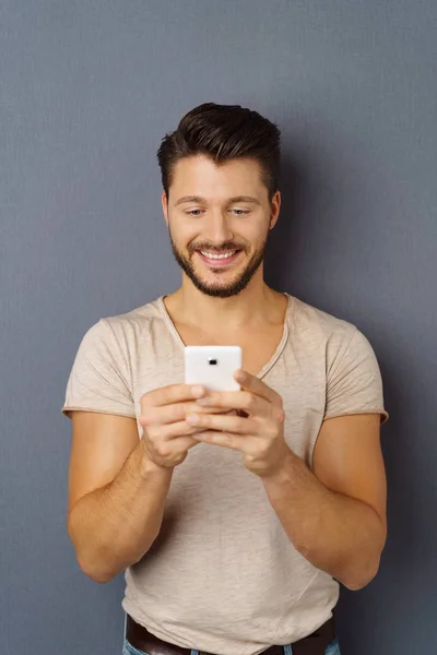 Młody człowiek uśmiechający się przy użyciu telefonu komórkowego — Zdjęcie stockowe
