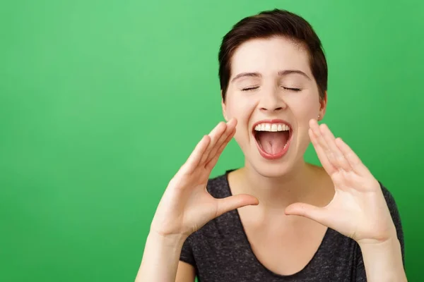 Mujer joven gritando sobre fondo verde — Foto de Stock