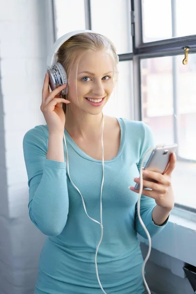 Femme souriante écoutant de la musique sur smartphone — Photo