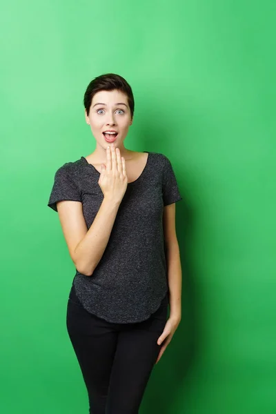 Jonge verrast vrouw stond op groene achtergrond — Stockfoto