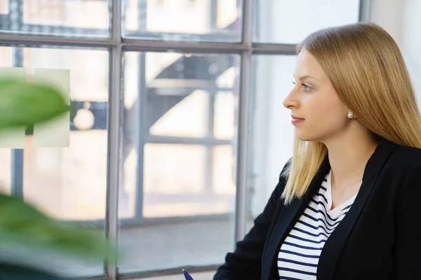 Mujer rubia joven mirando a través de la ventana —  Fotos de Stock