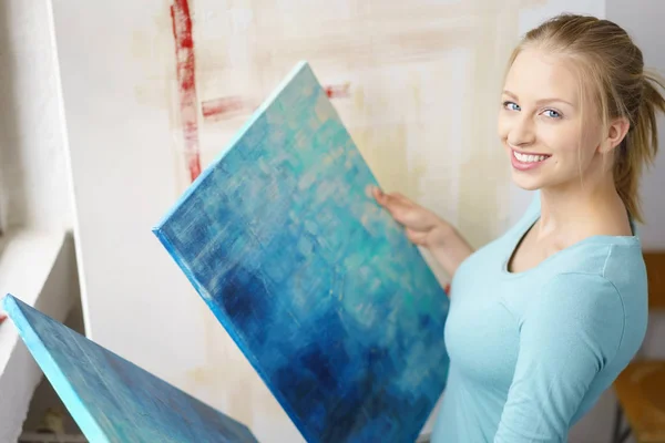 Young blonde woman viewing paintings in atelier — Stock Photo, Image