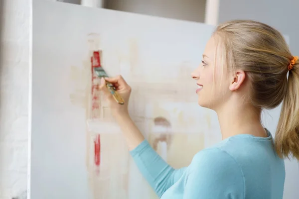 Jovem mulher loira pintura quadro no atelier — Fotografia de Stock