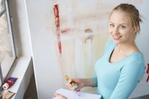 Mujer sonriente posando en el taller mientras pinta —  Fotos de Stock