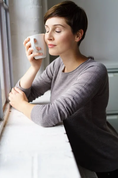 Młoda kobieta milczący kawie w oknie — Zdjęcie stockowe