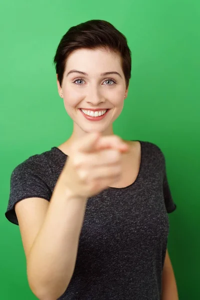 Unga leende kvinna som pekar på kamera — Stockfoto