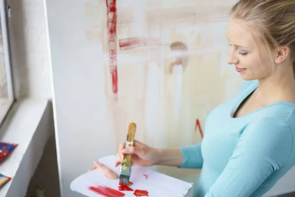 Giovane donna pittura con pennello in atelier — Foto Stock