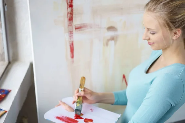 Młoda kobieta malowanie pędzlem w atelier — Zdjęcie stockowe