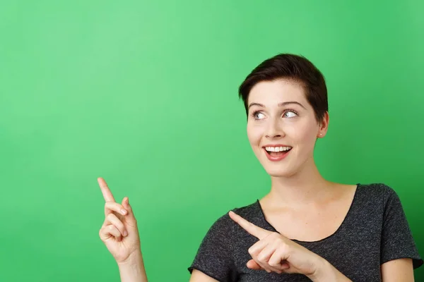 Mujer alegre apuntando al espacio de copia vacío — Foto de Stock