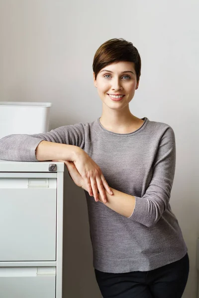 Junge lächelnde Frau lehnt an Aktenschrank — Stockfoto