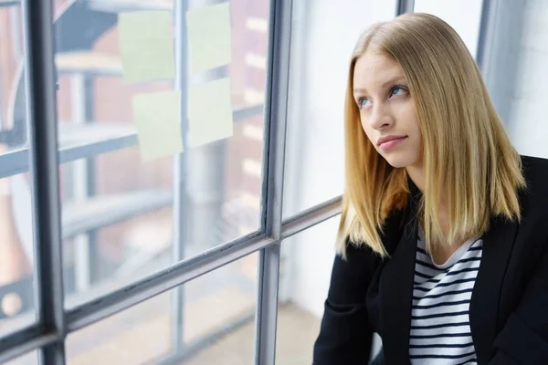 Unga allvarliga blond kvinna sitter vid fönstret — Stockfoto