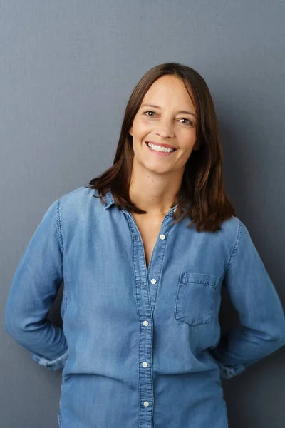 Smiling woman standing on grey background — Stock Photo, Image