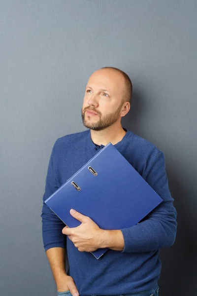 Thoughtful man holding closed ring binder — Stock Photo, Image