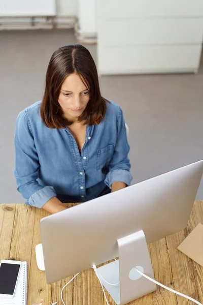 Jovem mulher sentada na frente do computador no escritório — Fotografia de Stock