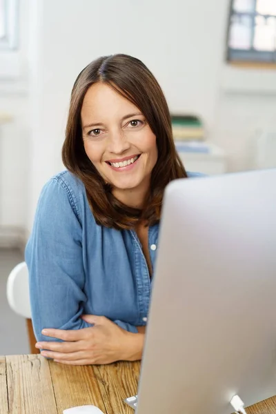 Lachende vrouw achter computer zit — Stockfoto