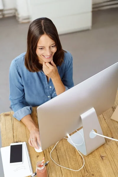 Lachende vrouw achter computer zit — Stockfoto
