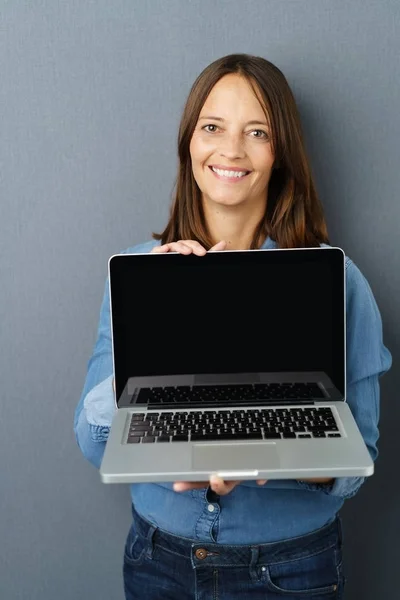 Lachende vrouw toont opengeklapte laptop — Stockfoto