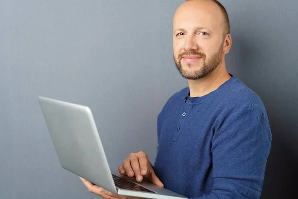 Usmívající se muž stál s otevřenou laptop — Stock fotografie