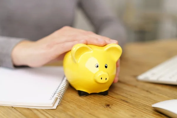 Vrouwelijke Handen Strelen Gele Piggy Bank Aan Balie — Stockfoto