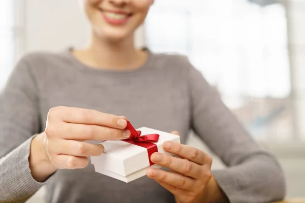 Smiling woman unwrapping gift box — Stock Photo, Image