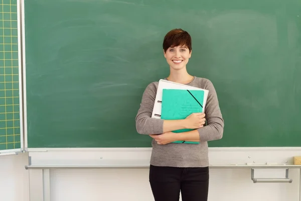 Woman against blackboard in classroom — Stock Photo, Image