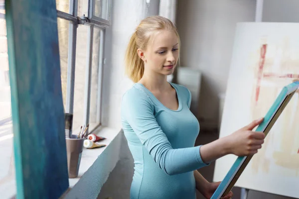 Young blonde woman holding paiting — Stock Photo, Image