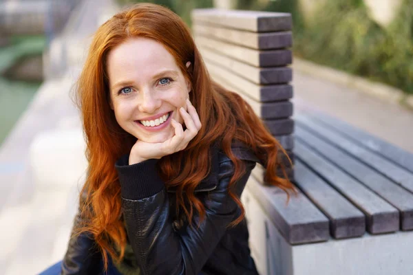 Attraente donna rossa sorridente seduta all'aperto — Foto Stock