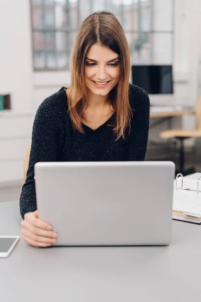 Pengusaha wanita muda tersenyum pada laptopnya — Stok Foto