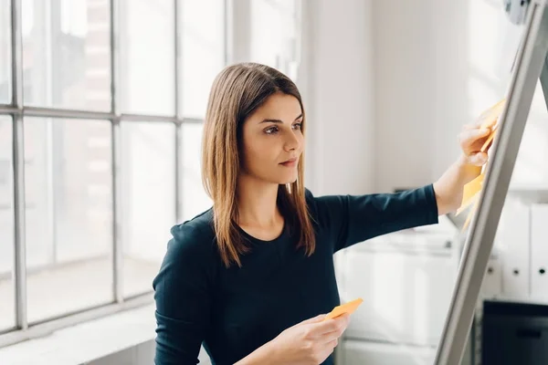 Mujer joven pegando notas adhesivas — Foto de Stock